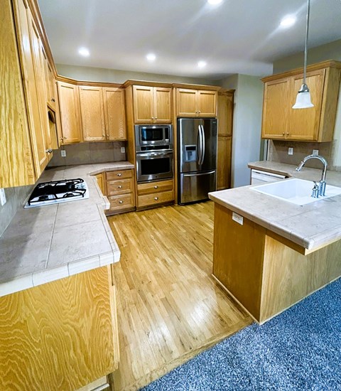 A kitchen with wooden cabinets and a white counter top.