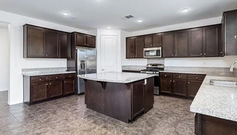 A kitchen with brown cabinets and a marble countertop.