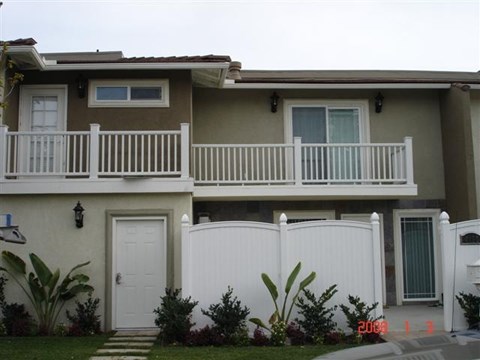 A two-story house with a white fence and a small front yard.