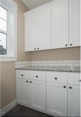 A kitchen with white cabinets and a tiled backsplash.