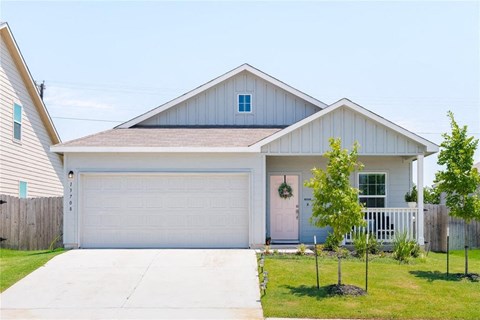 A white house with a grey roof and a white garage door.