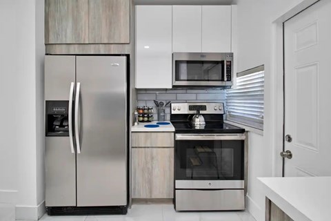 A modern kitchen with a stainless steel refrigerator and microwave above a stainless steel oven.