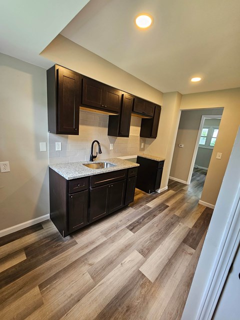 A kitchen with dark brown cabinets and a white countertop.