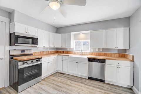 A kitchen with white cabinets and a wooden countertop.