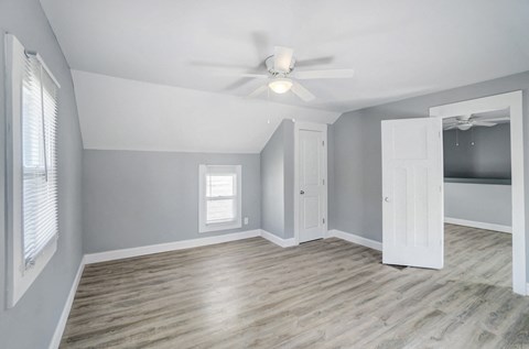 A room with a ceiling fan and a window with blinds.