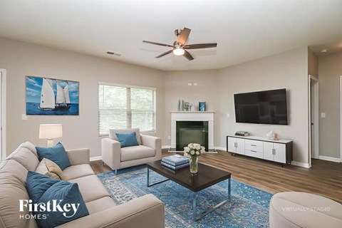 A living room with a white couch, a coffee table, a television, and a painting of a sailboat on the wall.