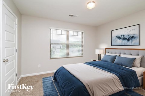 A bedroom with a large bed and a painting on the wall.