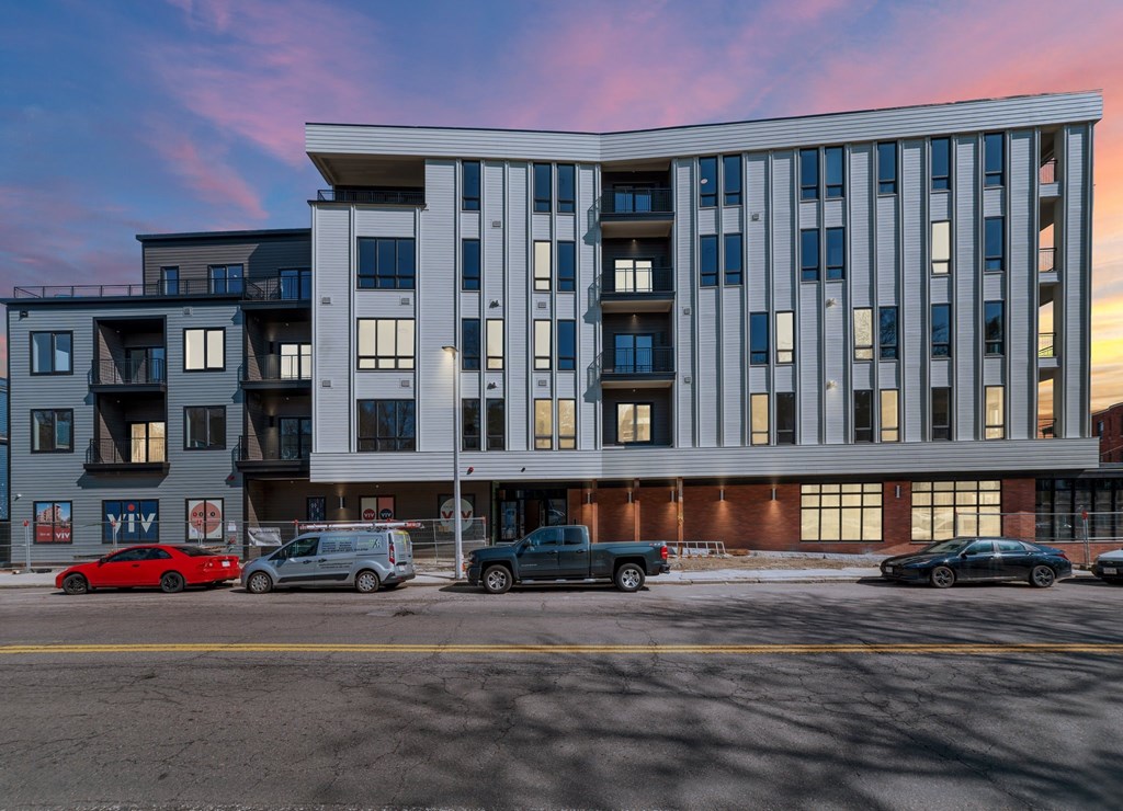 A modern apartment building with cars parked in front.