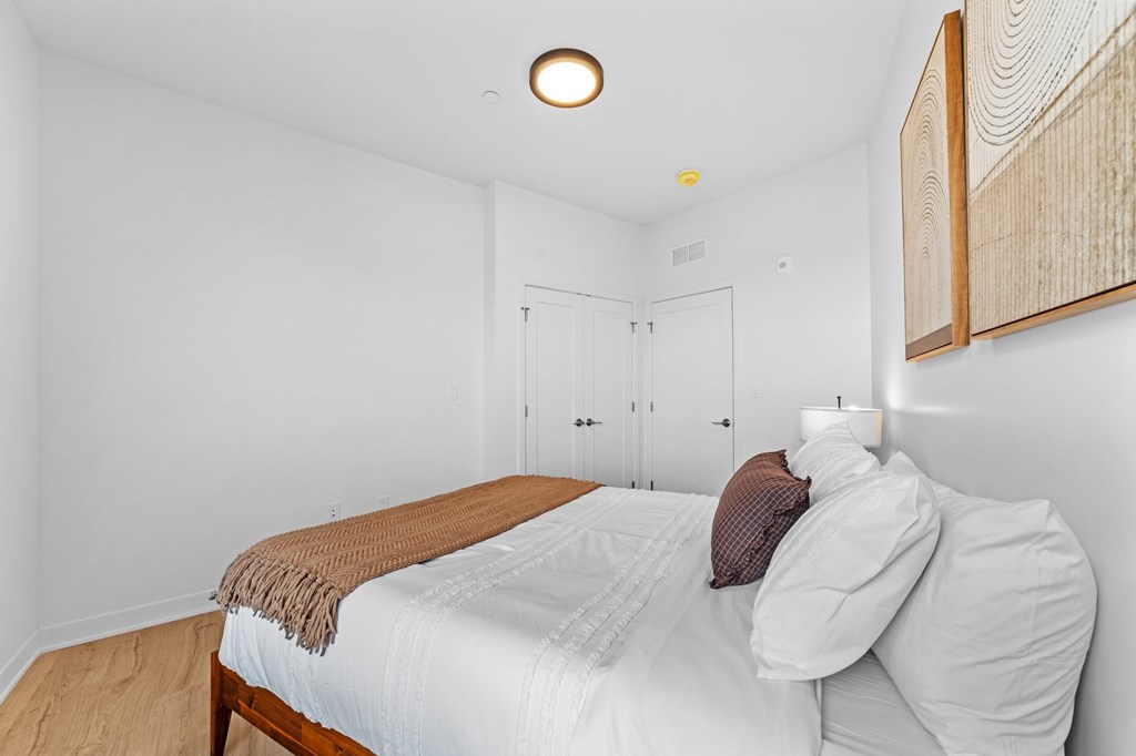 A bedroom with a bed, pillows, and a blanket.