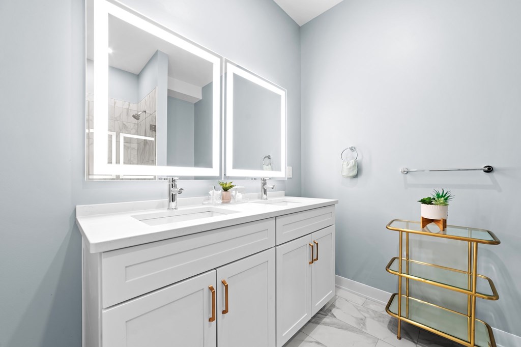 A bathroom with a white vanity and a gold shelf.