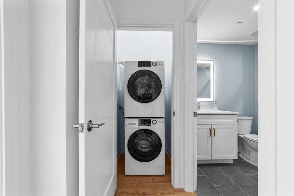 A white door opens to a laundry room with a washer and dryer.