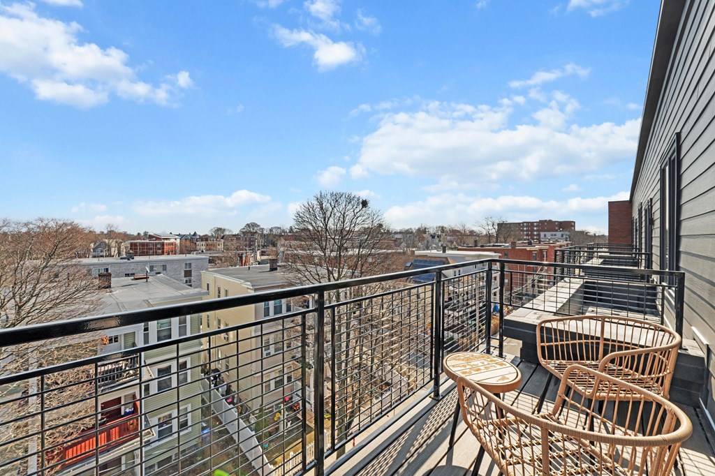 A balcony with a table and chairs overlooks a cityscape.