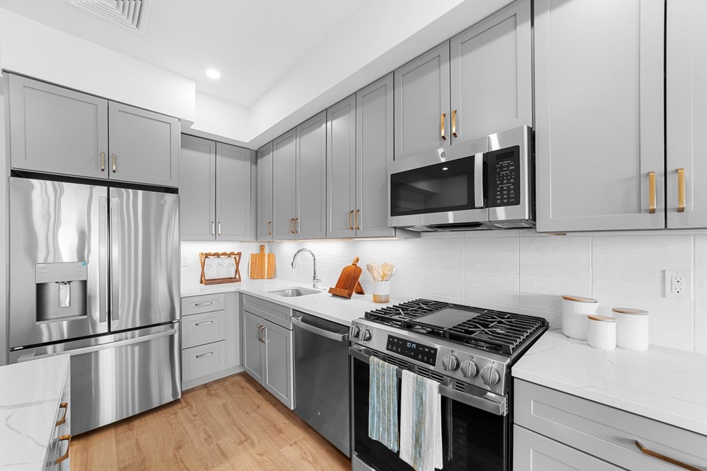 A modern kitchen with a stainless steel refrigerator, microwave, and oven.