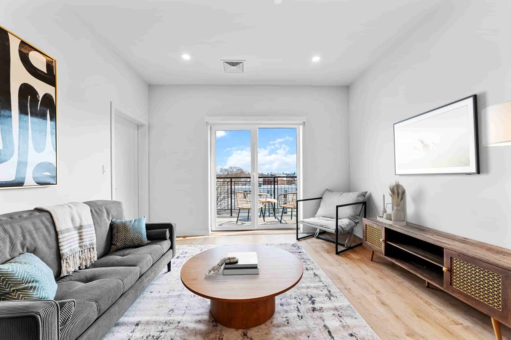A living room with a grey couch, a coffee table, and a large window.