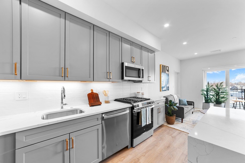 A modern kitchen with a white countertop and grey cabinets.
