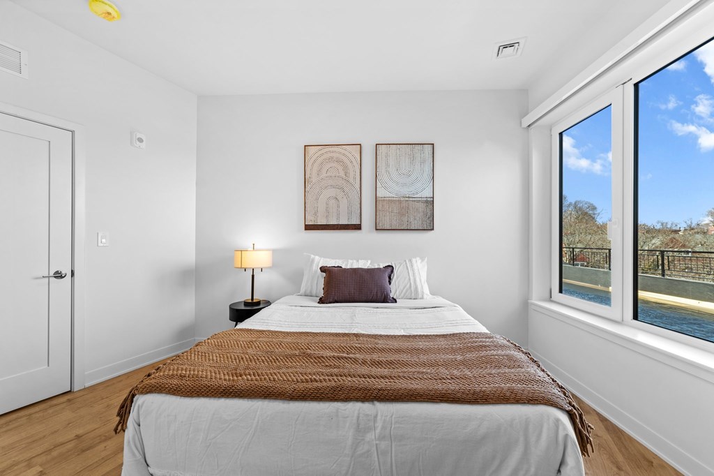 A bedroom with a large bed and a view of a pool through the window.