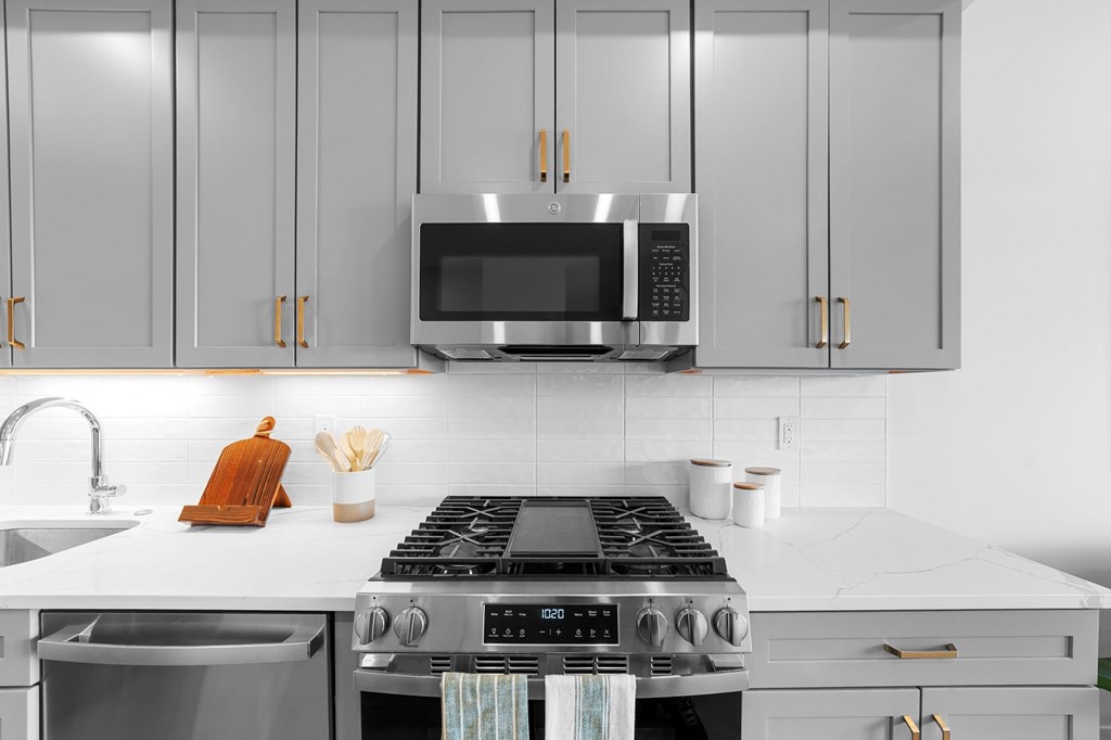 A modern kitchen with a stove, microwave, and cabinets.