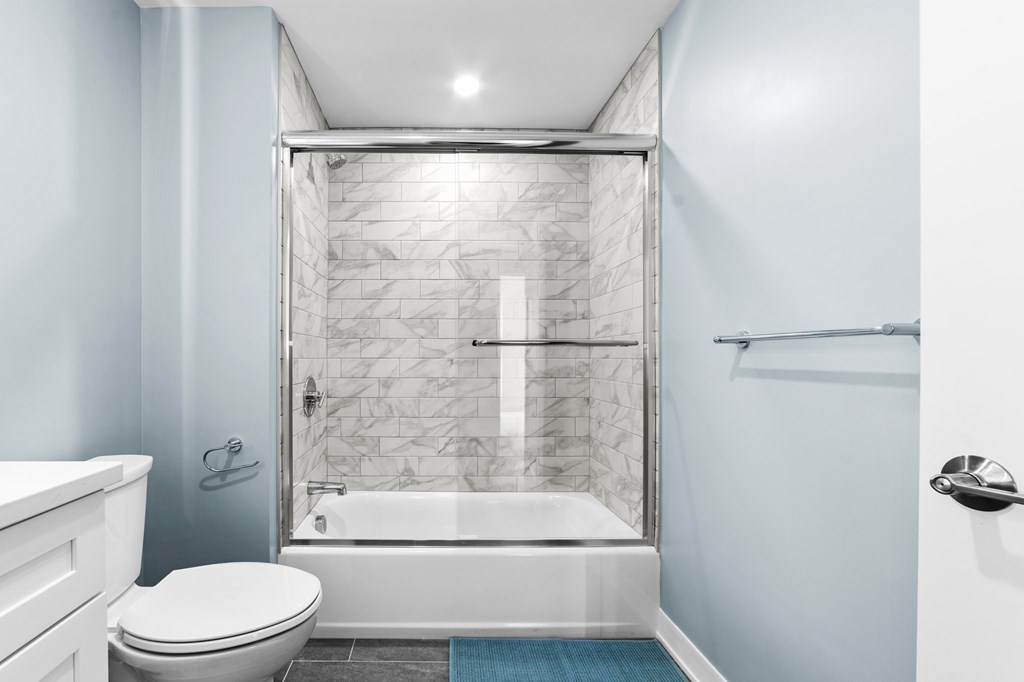 A white toilet sits next to a walk-in shower with a glass door.