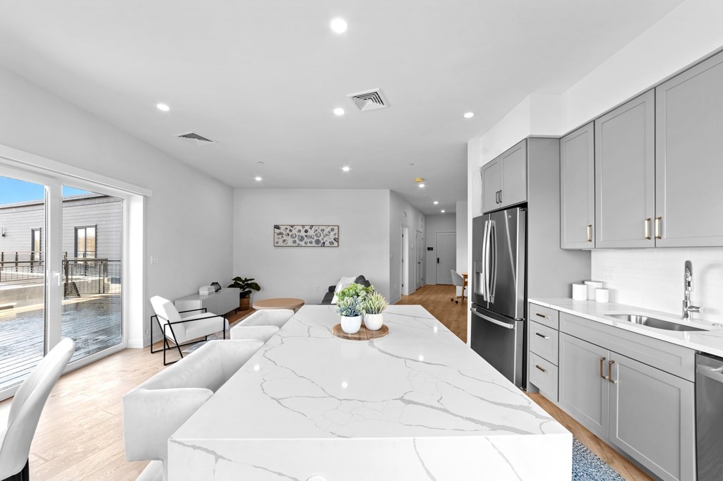 A modern kitchen with a marble island and a view of a waterfront.