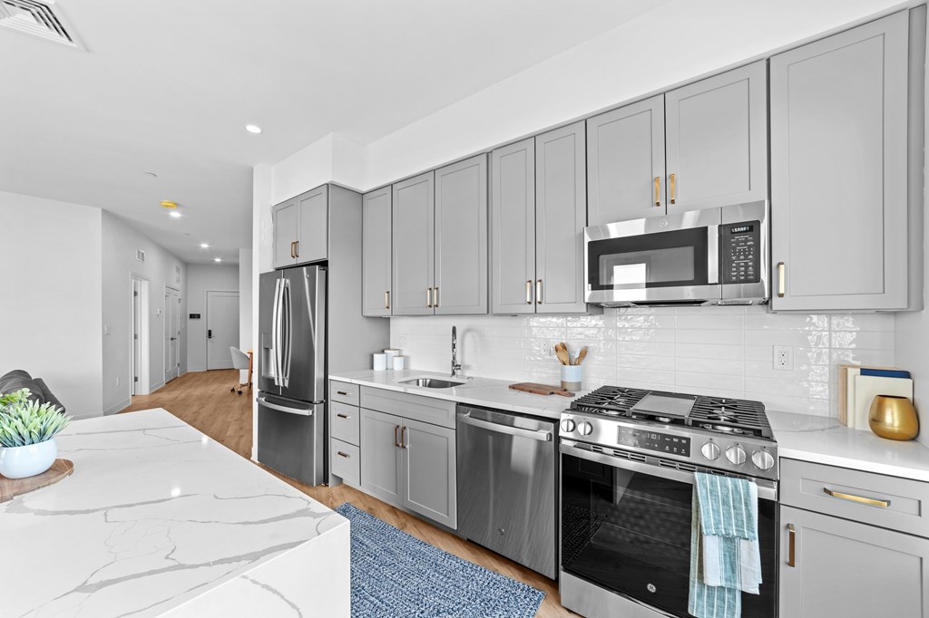 A modern kitchen with a white countertop and stainless steel appliances.