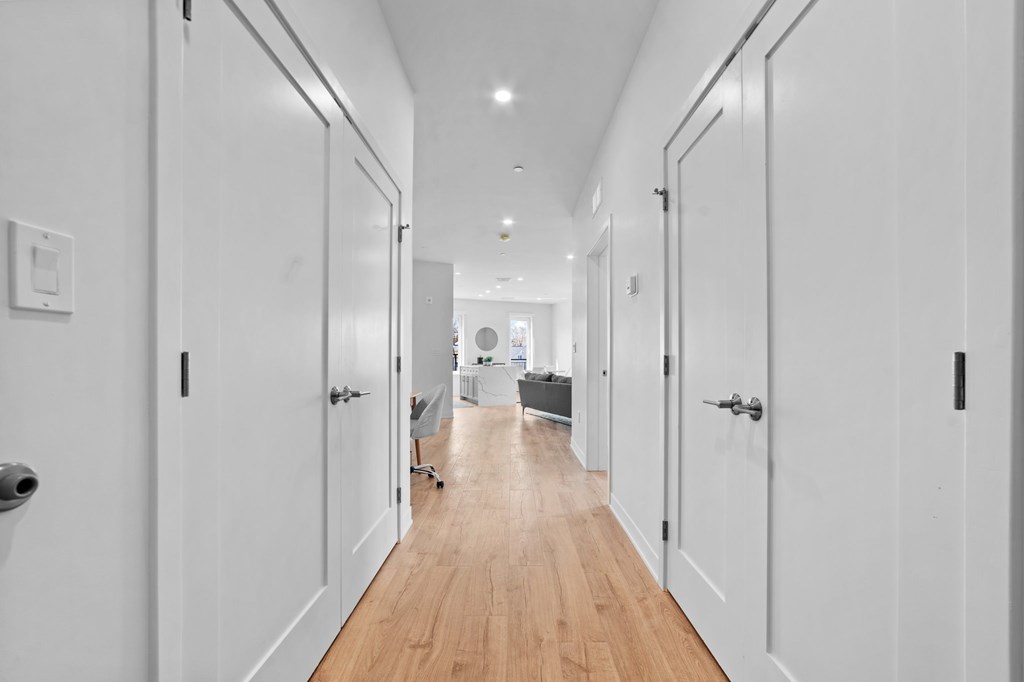 A long hallway with white doors and a light wood floor.