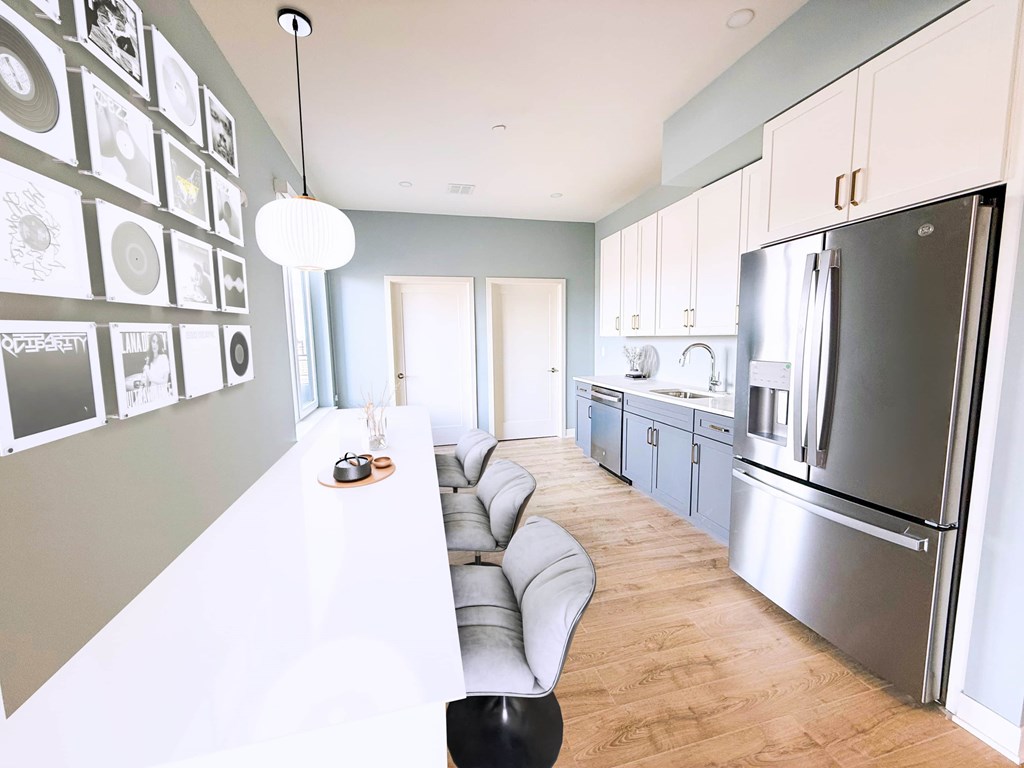 A modern kitchen with a long white counter and a black chair.