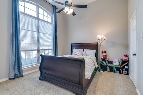 A bedroom with a large bed and a ceiling fan.