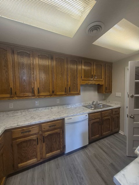 A kitchen with wooden cabinets and a white dishwasher.