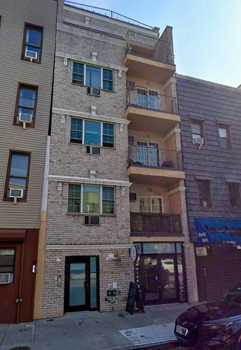 A building with a balcony and a car parked in front.