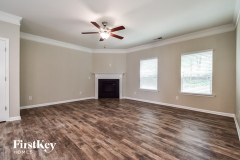 A spacious room with a fireplace and wood flooring.