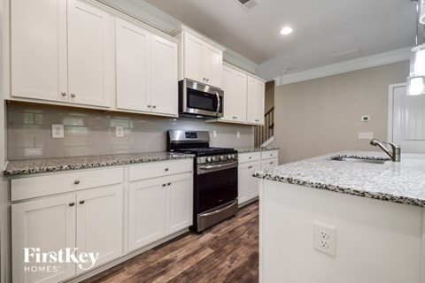 A kitchen with white cabinets and a granite countertop.
