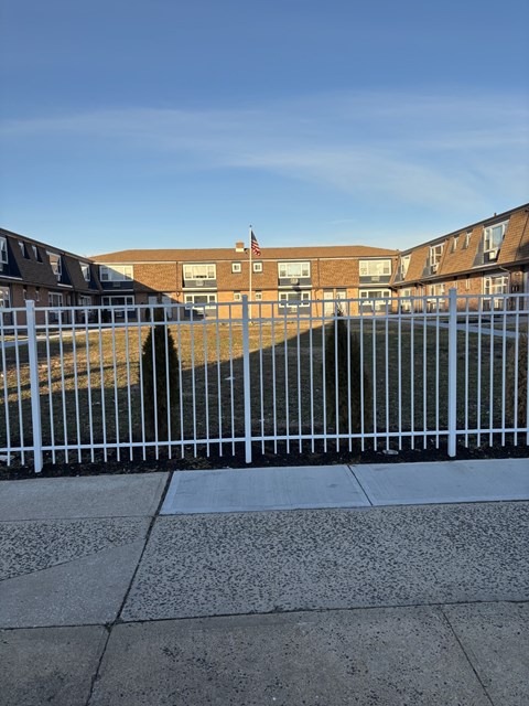 A white fence in front of a building with a flag on it.