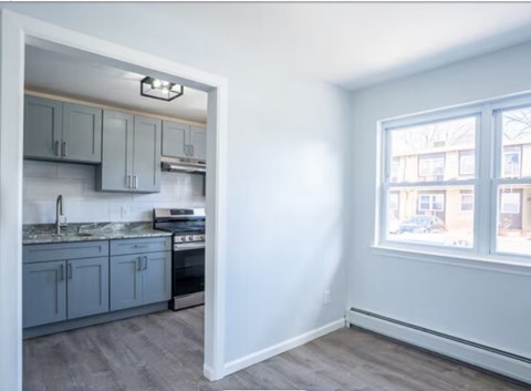 A kitchen with a sink, stove, and cabinets is visible through a doorway.