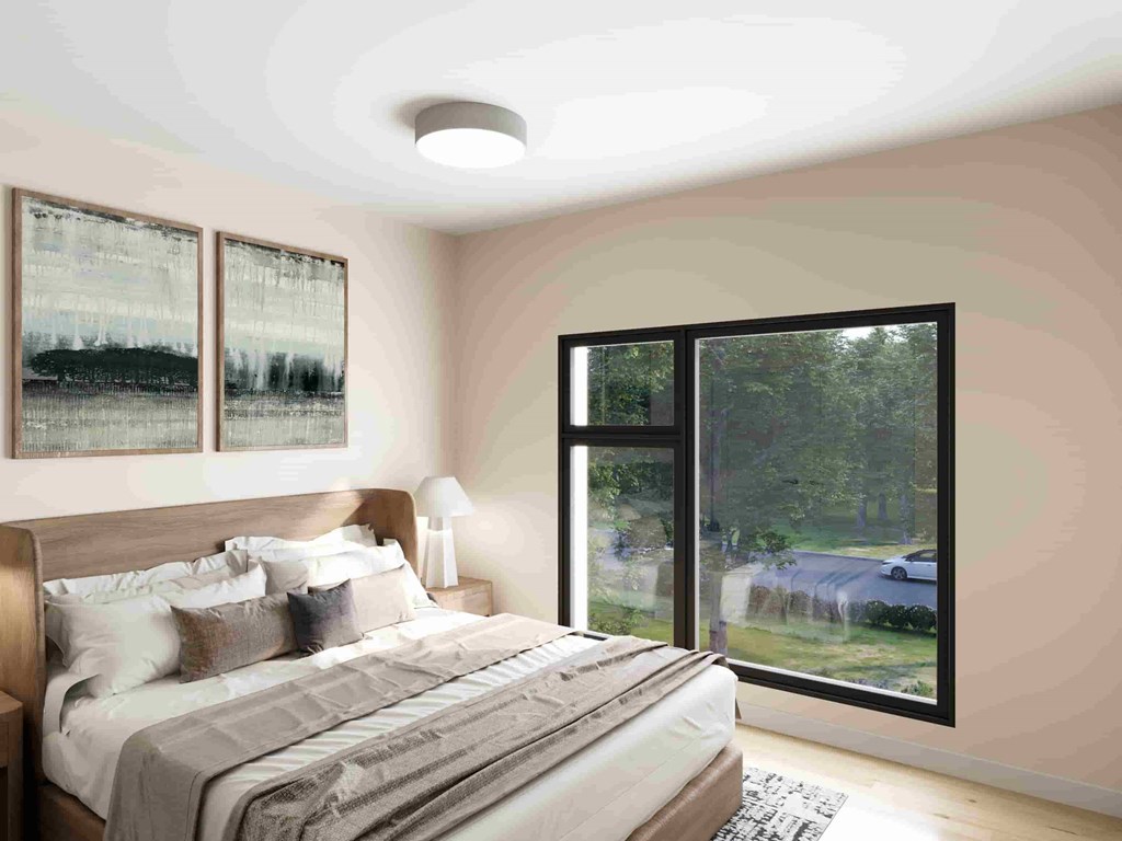 A bedroom with a large bed and a view of a car and trees outside.