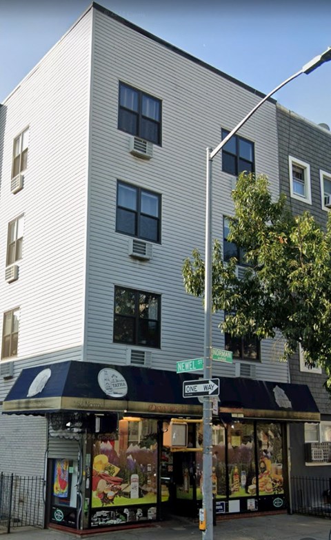 A street view of a building with a storefront at the corner.