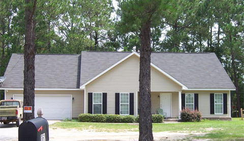 A house with a grey roof and a white garage door.