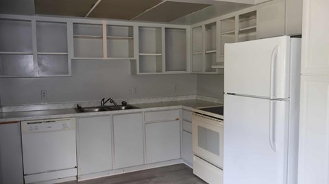 A white kitchen with a refrigerator on the right.