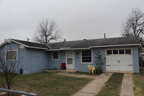 A blue house with a white garage door and a red chair.