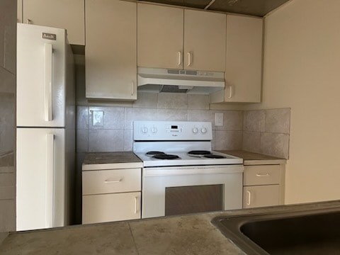 A kitchen with a white fridge, stove, and oven.
