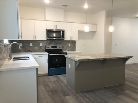 A kitchen with a white counter top and a microwave above it.