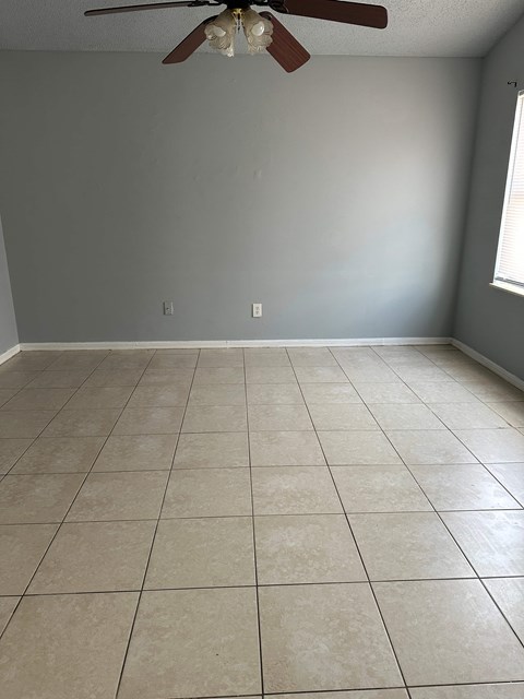 A room with a ceiling fan and tile flooring.