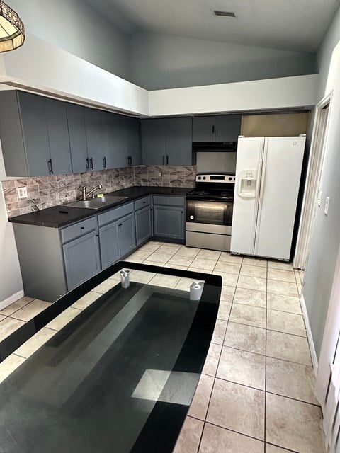 A kitchen with a black granite countertop and a white refrigerator.