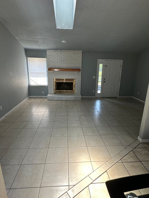 A living room with a fireplace and tile flooring.