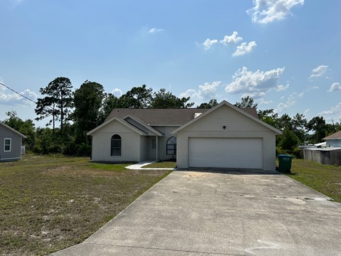 A house with a garage and a driveway in front of it.