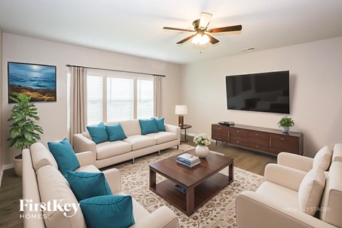 A living room with a white couch, a coffee table, a flat screen TV, and a ceiling fan.