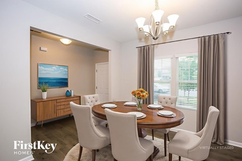 A dining room with a wooden table and chairs, a chandelier, and a painting on the wall.