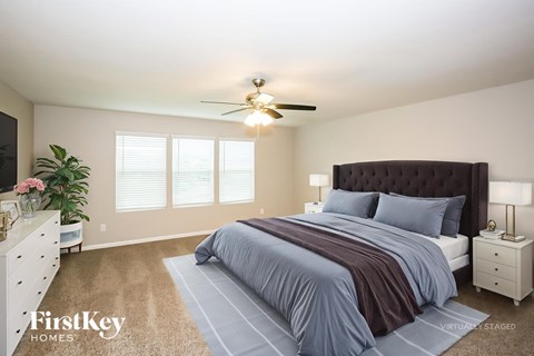 A bedroom with a large bed and a ceiling fan.