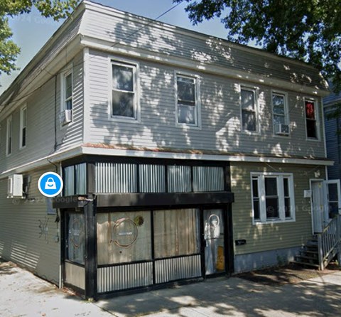 A grey house with a blue sign on the front.