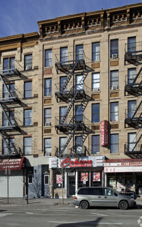 A grey car is parked in front of a building with a red sign that says "Dragon".