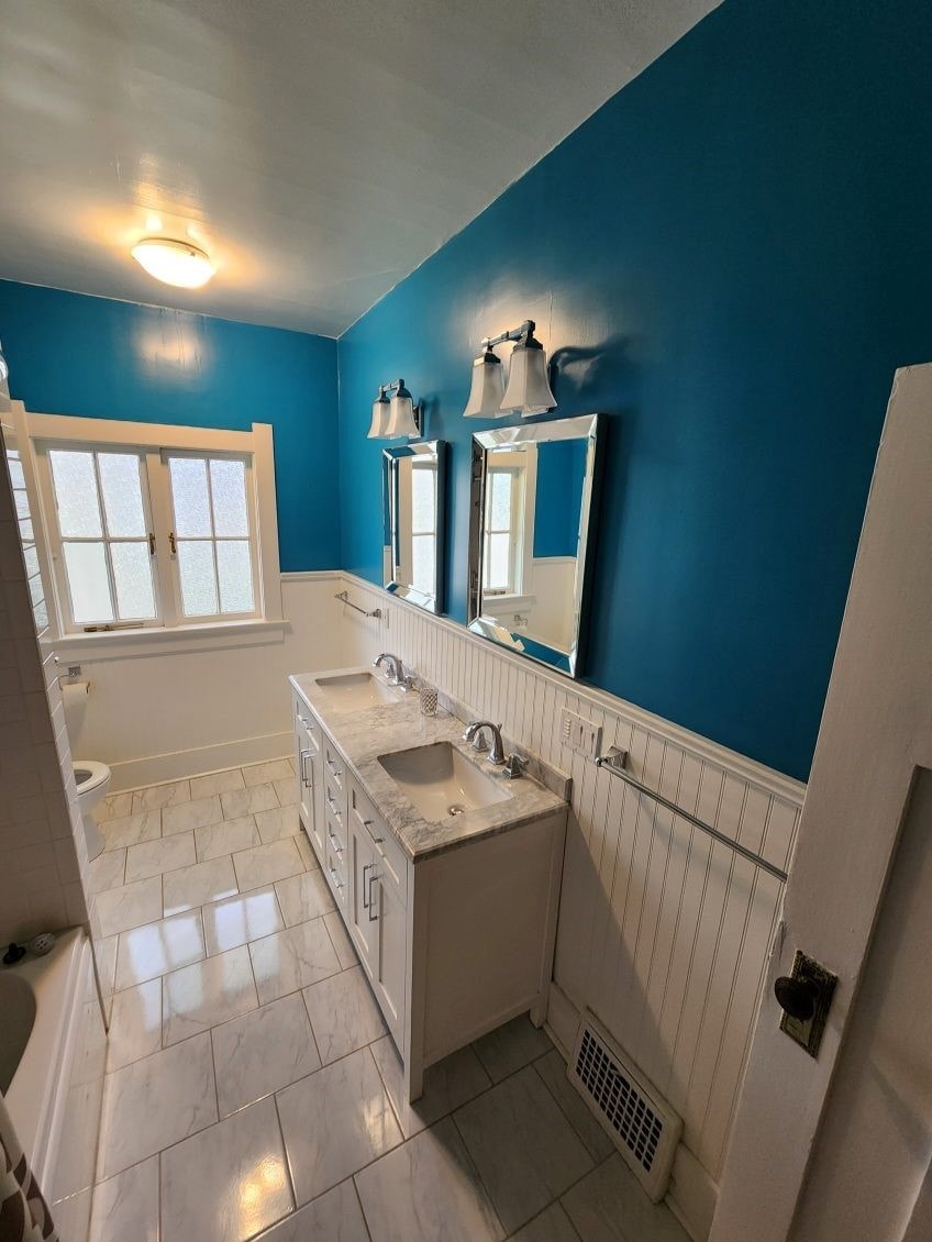 A bathroom with blue walls and a white vanity.